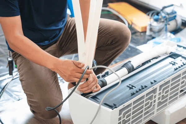 Neal HVAC technician repairing an outdoor AC unit beside a Georgetown home on a warm Texas afternoon