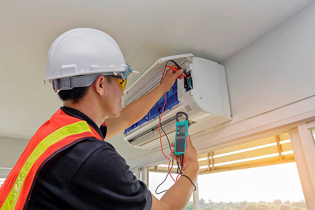 Experienced HVAC technician measuring system performance and airflow inside residential utility closet