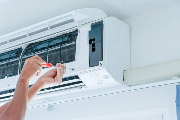 Technician inspecting outdoor AC unit at Liberty Hill home with weak afternoon cooling