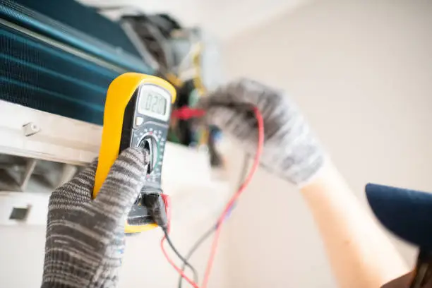 HVAC technician testing electrical components and airflow during urgent residential AC system diagnosis