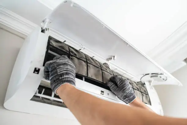 Technician diagnosing residential AC system after sudden cooling failure on hot afternoon