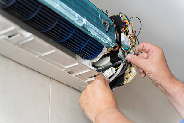 Technician inspecting outdoor AC unit at suburban home with poor indoor cooling